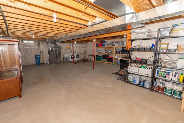 unfinished below grade area featuring heating unit and independent washer and dryer