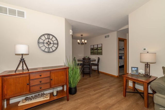 interior space featuring visible vents, light wood finished floors, baseboards, and a notable chandelier