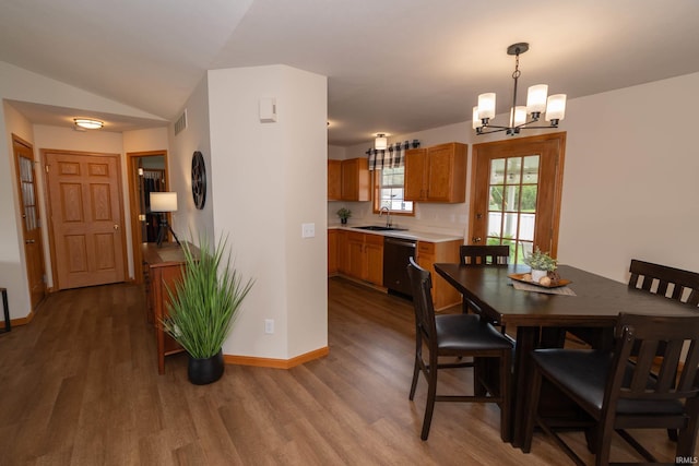 dining space with a chandelier, visible vents, wood finished floors, baseboards, and lofted ceiling