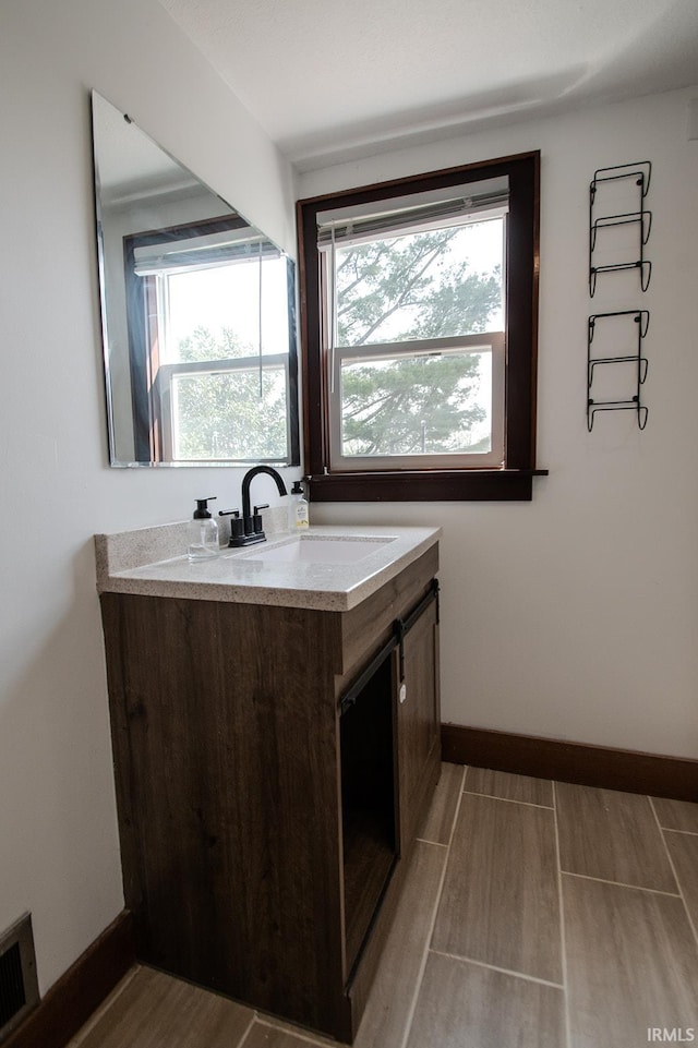 bathroom with baseboards, visible vents, a wealth of natural light, and vanity
