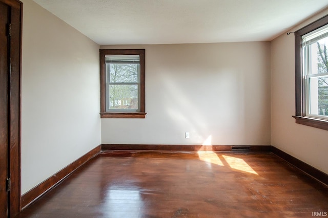 spare room featuring baseboards and wood finished floors