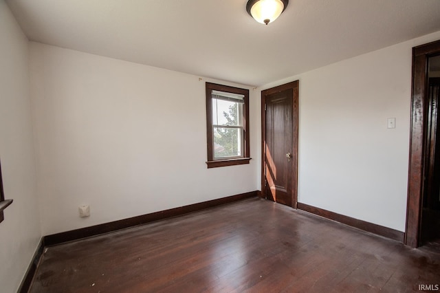 spare room featuring baseboards and dark wood finished floors