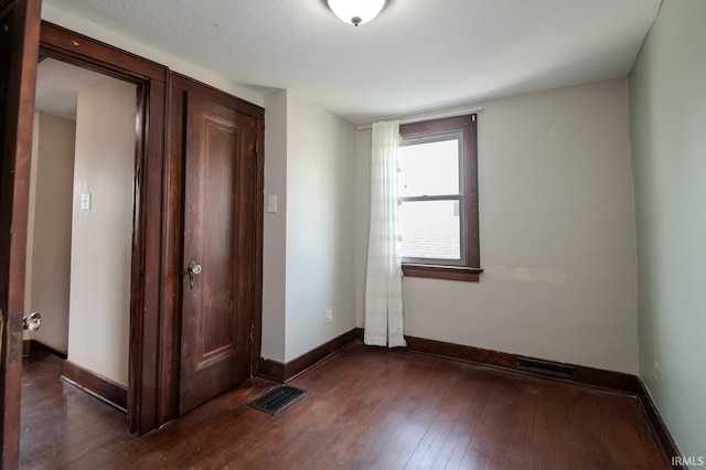 unfurnished bedroom featuring baseboards, visible vents, and dark wood-type flooring