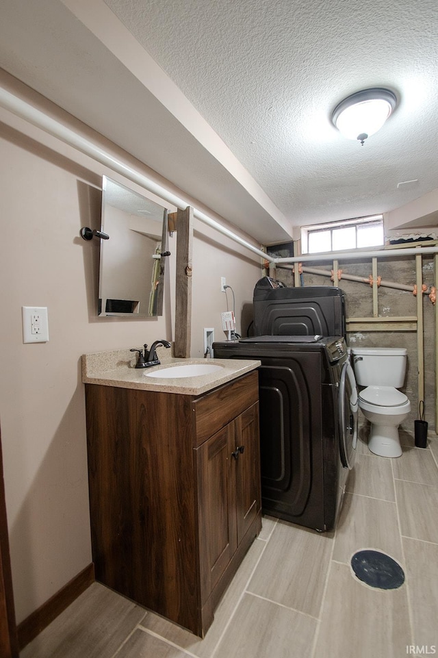 laundry area featuring a sink, a textured ceiling, laundry area, and washer / dryer