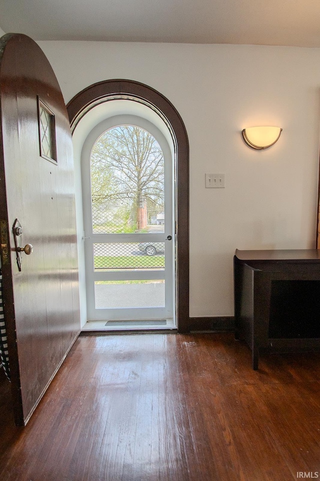 foyer entrance featuring arched walkways and hardwood / wood-style floors