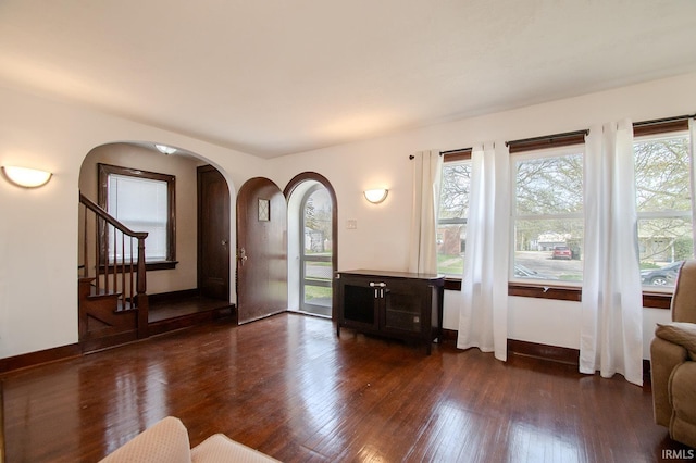 entryway featuring arched walkways, dark wood-style flooring, and a wealth of natural light