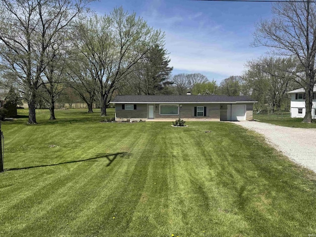 rear view of property with a garage, a yard, and driveway