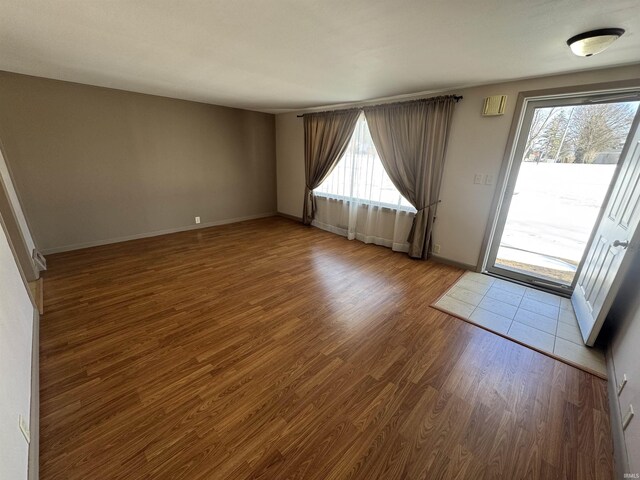 unfurnished room featuring baseboards, plenty of natural light, and wood finished floors