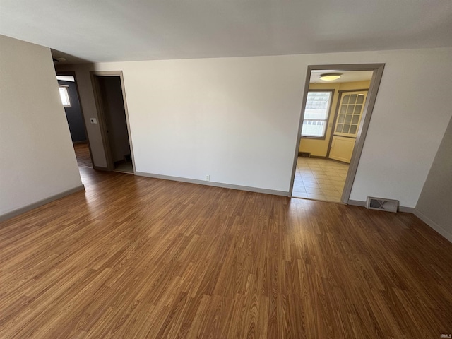 empty room featuring baseboards, visible vents, and wood finished floors