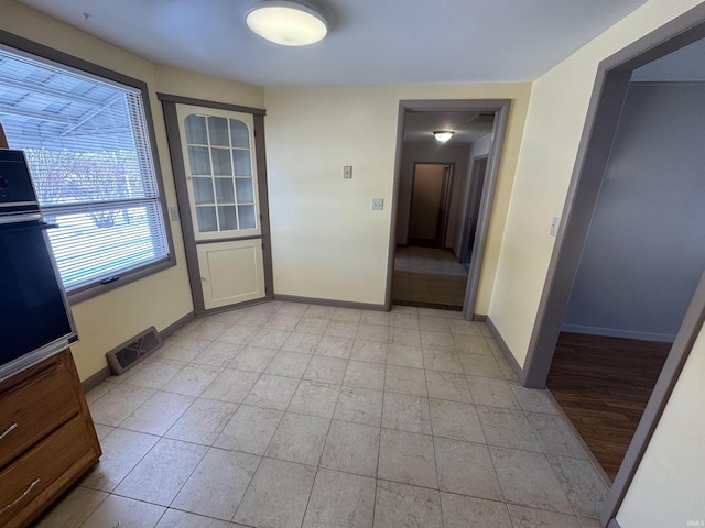 interior space with baseboards, visible vents, and light tile patterned floors