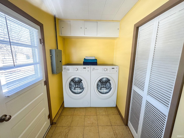 washroom with electric panel, washing machine and clothes dryer, cabinet space, light tile patterned floors, and baseboards