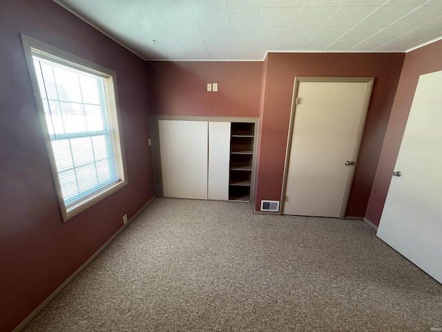 unfurnished bedroom with visible vents, carpet flooring, baseboards, and a closet