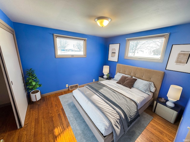 bedroom with visible vents, baseboards, and wood finished floors