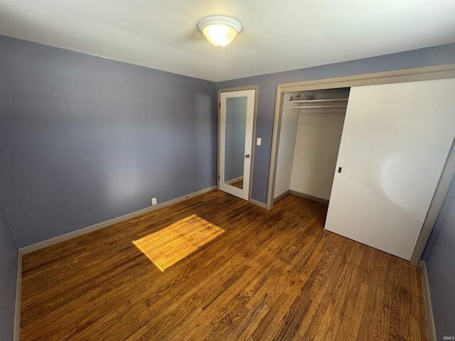 unfurnished bedroom featuring baseboards, wood finished floors, and a closet