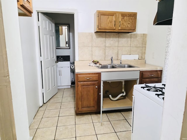 kitchen featuring white gas range oven, a sink, light tile patterned flooring, and light countertops