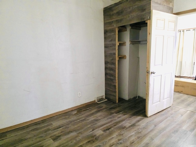 unfurnished bedroom featuring baseboards, a closet, and wood finished floors