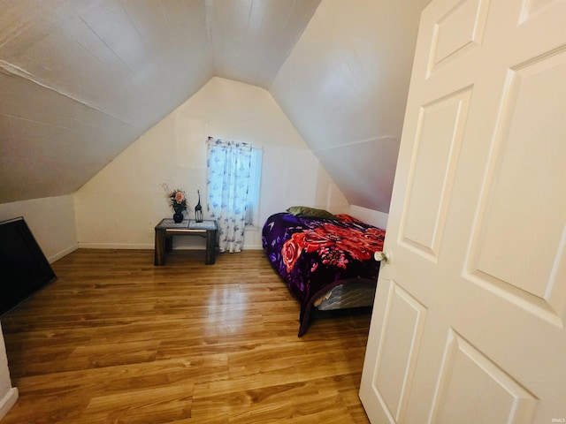 bedroom featuring baseboards, vaulted ceiling, and light wood-style floors