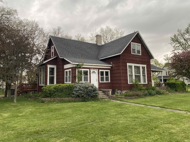 view of front of home featuring a front lawn, roof with shingles, and a chimney