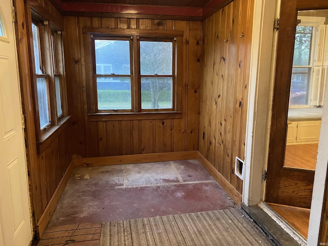 unfurnished room featuring baseboards, wood walls, and a wealth of natural light