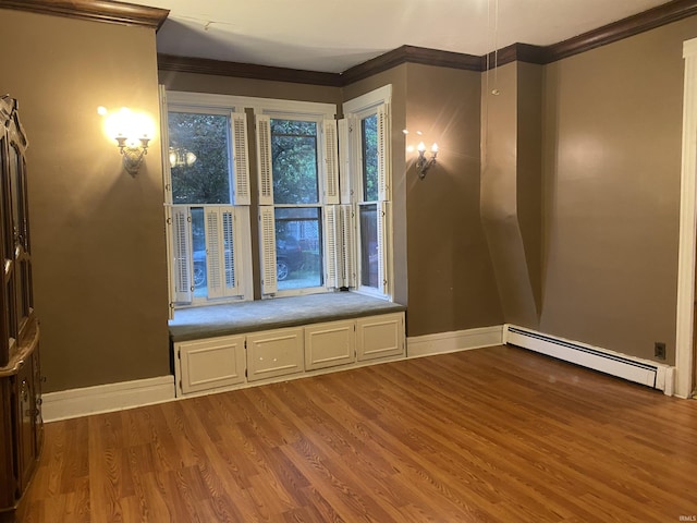 spare room featuring crown molding, a baseboard radiator, baseboards, and wood finished floors