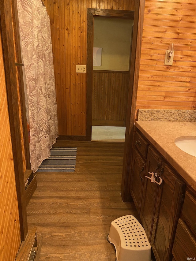 bathroom featuring hardwood / wood-style flooring, vanity, wood walls, and curtained shower