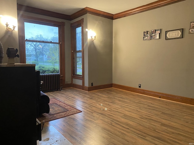 unfurnished room with radiator heating unit, baseboards, ornamental molding, and wood finished floors