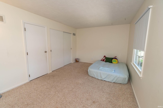 bedroom featuring baseboards, carpet flooring, and visible vents