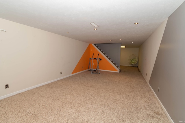 finished basement with baseboards, recessed lighting, stairs, and light carpet