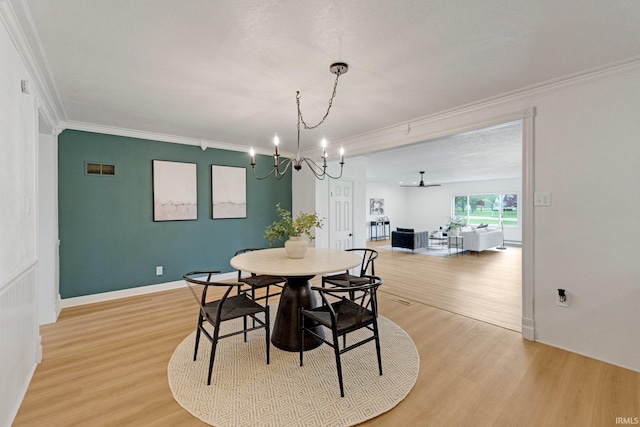 dining area featuring crown molding, light wood-style flooring, baseboards, and a chandelier