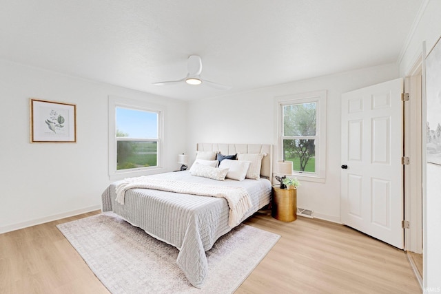 bedroom featuring baseboards, ceiling fan, light wood-style flooring, and visible vents