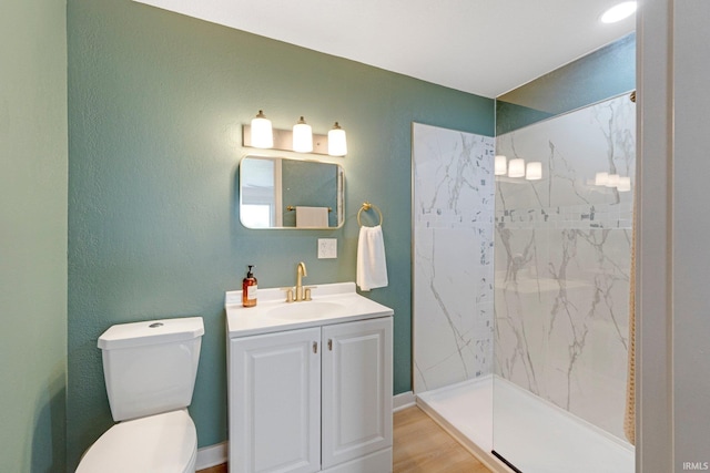 bathroom featuring vanity, a marble finish shower, wood finished floors, and toilet