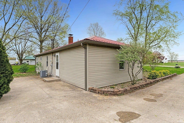 view of property exterior featuring a patio area, central air condition unit, and a chimney