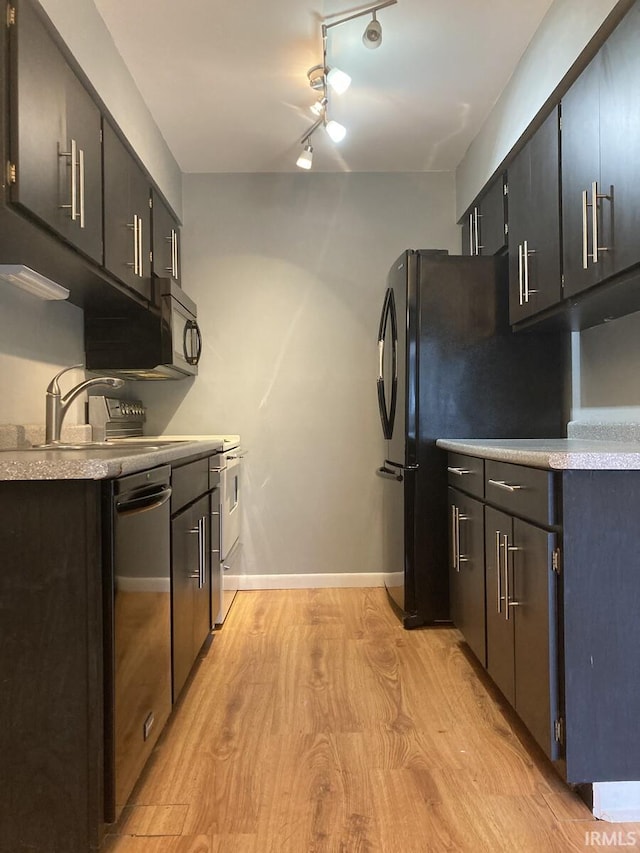 kitchen with black microwave, stainless steel dishwasher, light wood-type flooring, light countertops, and a sink
