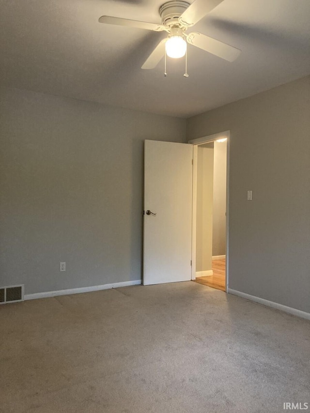 carpeted empty room with visible vents, a ceiling fan, and baseboards