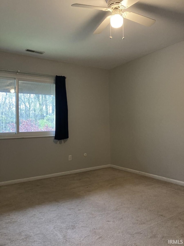 carpeted empty room with baseboards, ceiling fan, and visible vents