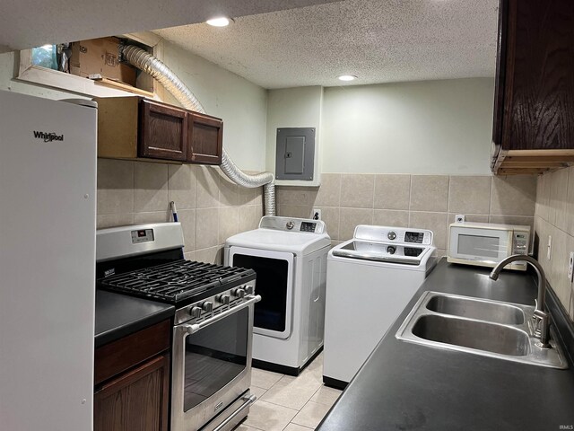 washroom featuring laundry area, light tile patterned flooring, electric panel, separate washer and dryer, and a sink