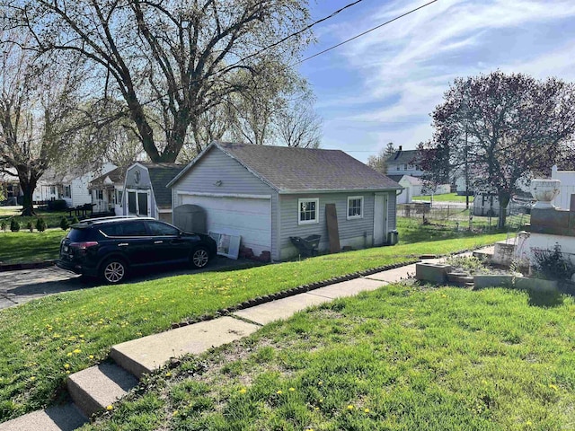 view of home's exterior with roof with shingles, a garage, fence, an outdoor structure, and a yard