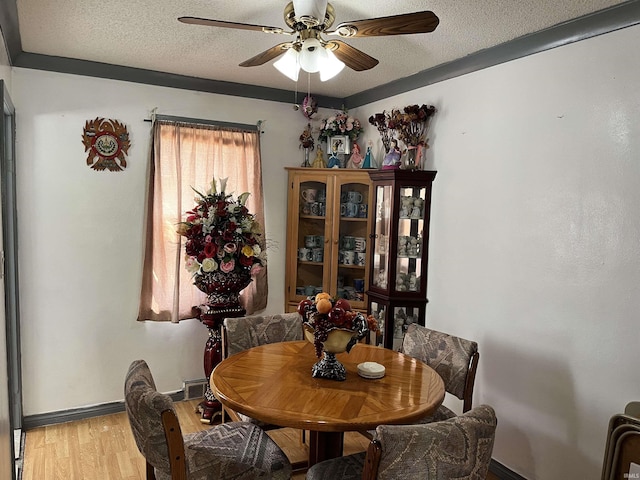 dining area with a ceiling fan, a textured ceiling, baseboards, and light wood finished floors