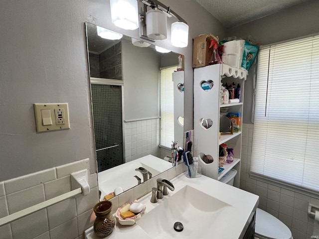full bathroom with vanity, toilet, tile walls, a wainscoted wall, and a tile shower