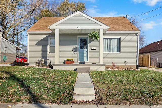bungalow-style house featuring a porch, a shingled roof, and a front yard