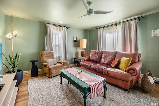living area featuring baseboards, light wood-style flooring, and ceiling fan