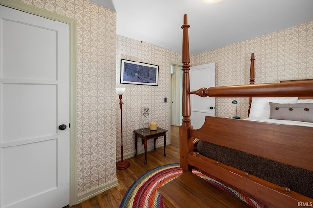 bedroom with baseboards, wallpapered walls, and wood finished floors