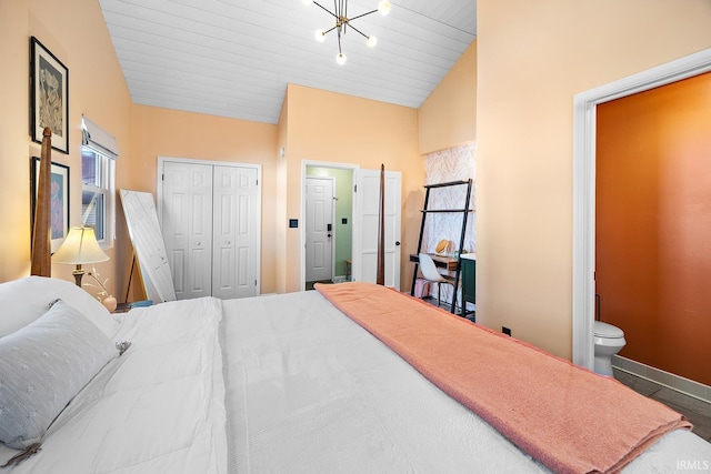 bedroom with a closet, baseboards, ensuite bath, and vaulted ceiling