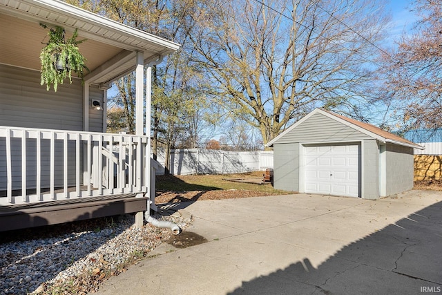 exterior space featuring an outdoor structure, a garage, fence, and concrete driveway