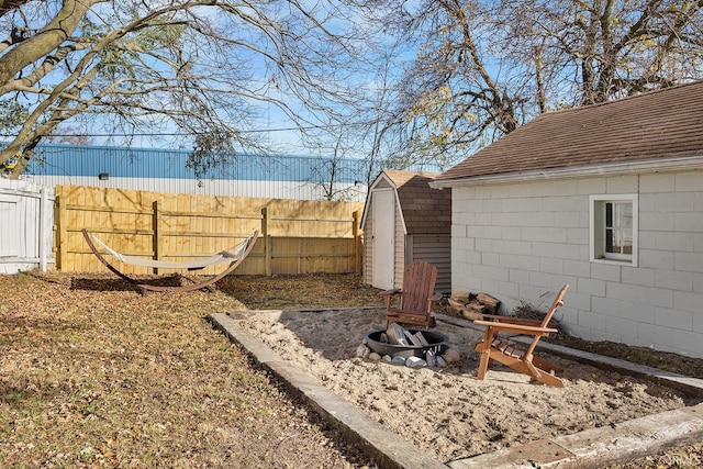 view of yard featuring fence, an outbuilding, an outdoor fire pit, and a storage shed