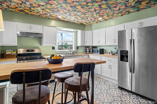 kitchen featuring a sink, wood counters, stainless steel appliances, and under cabinet range hood