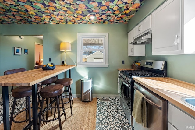 kitchen with wooden counters, baseboards, white cabinetry, under cabinet range hood, and appliances with stainless steel finishes