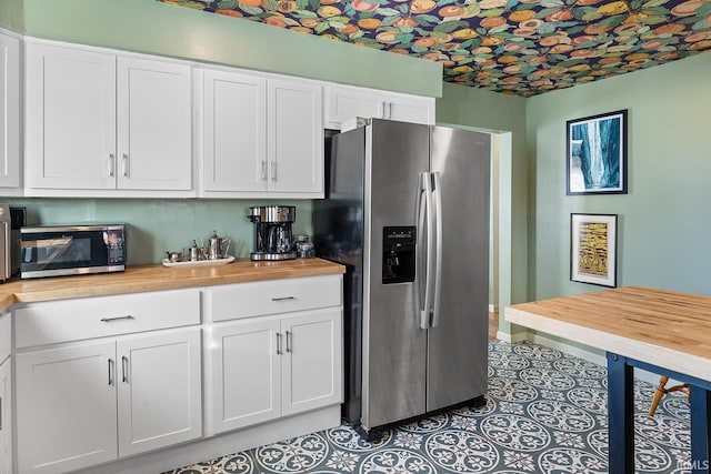 kitchen featuring wood counters, appliances with stainless steel finishes, an ornate ceiling, and white cabinetry