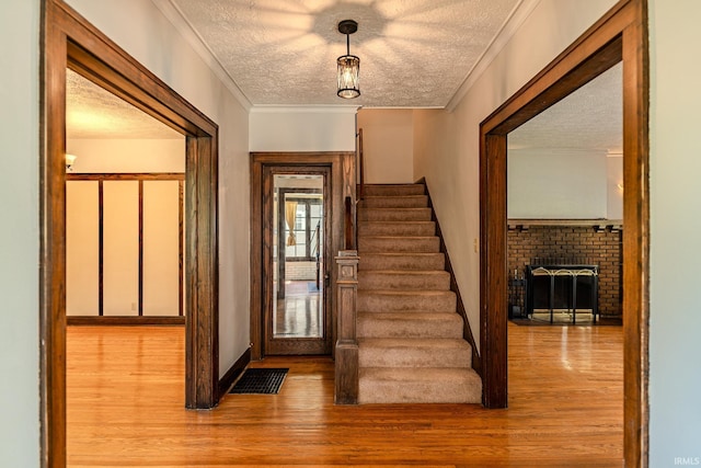 interior space with a textured ceiling, a brick fireplace, wood finished floors, and stairway