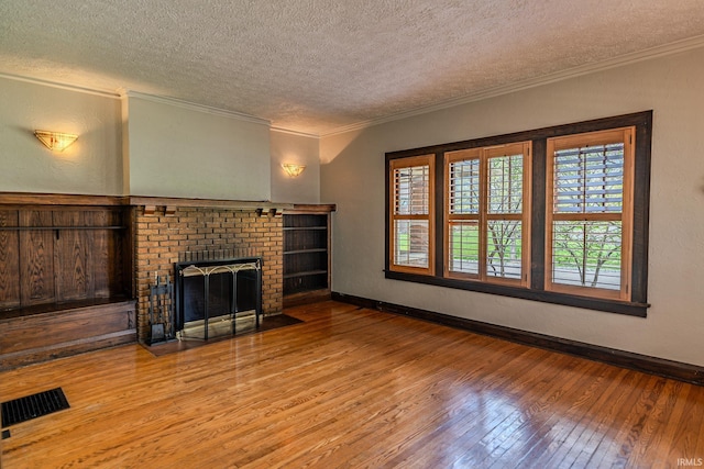 unfurnished living room with visible vents, crown molding, hardwood / wood-style floors, baseboards, and a textured ceiling